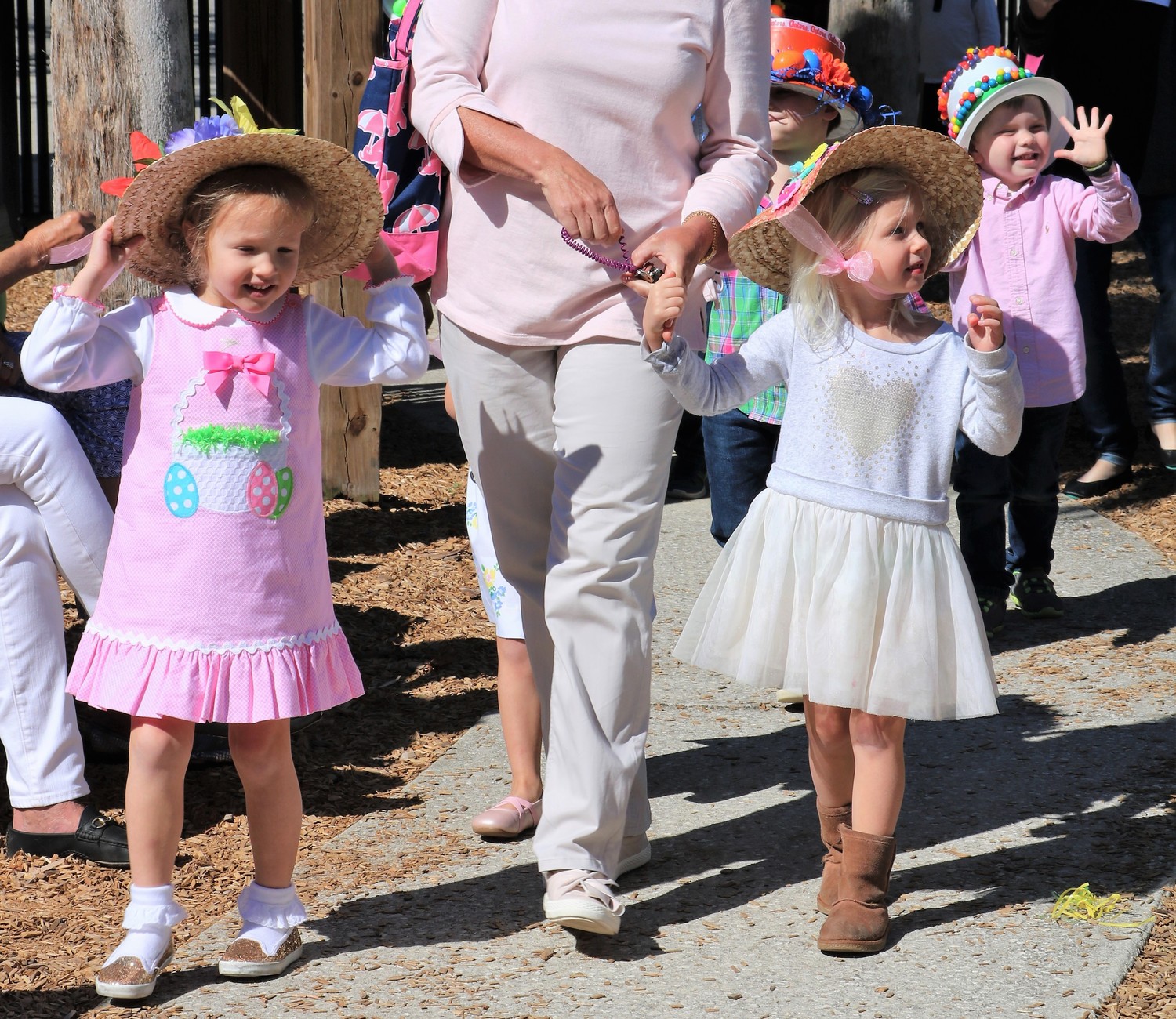 Children dressed in Easter attire smile and wave at spectators.